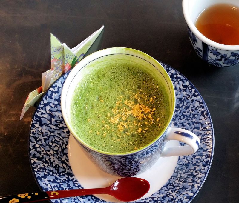 green tea latte in blue cup with gold leaf sprinkled on top