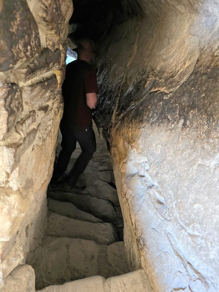 man walking through narrow stone passageway